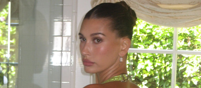 Hailey Bieber in a chartreuse halter with a slicked-back bun and an oval diamond drop earring